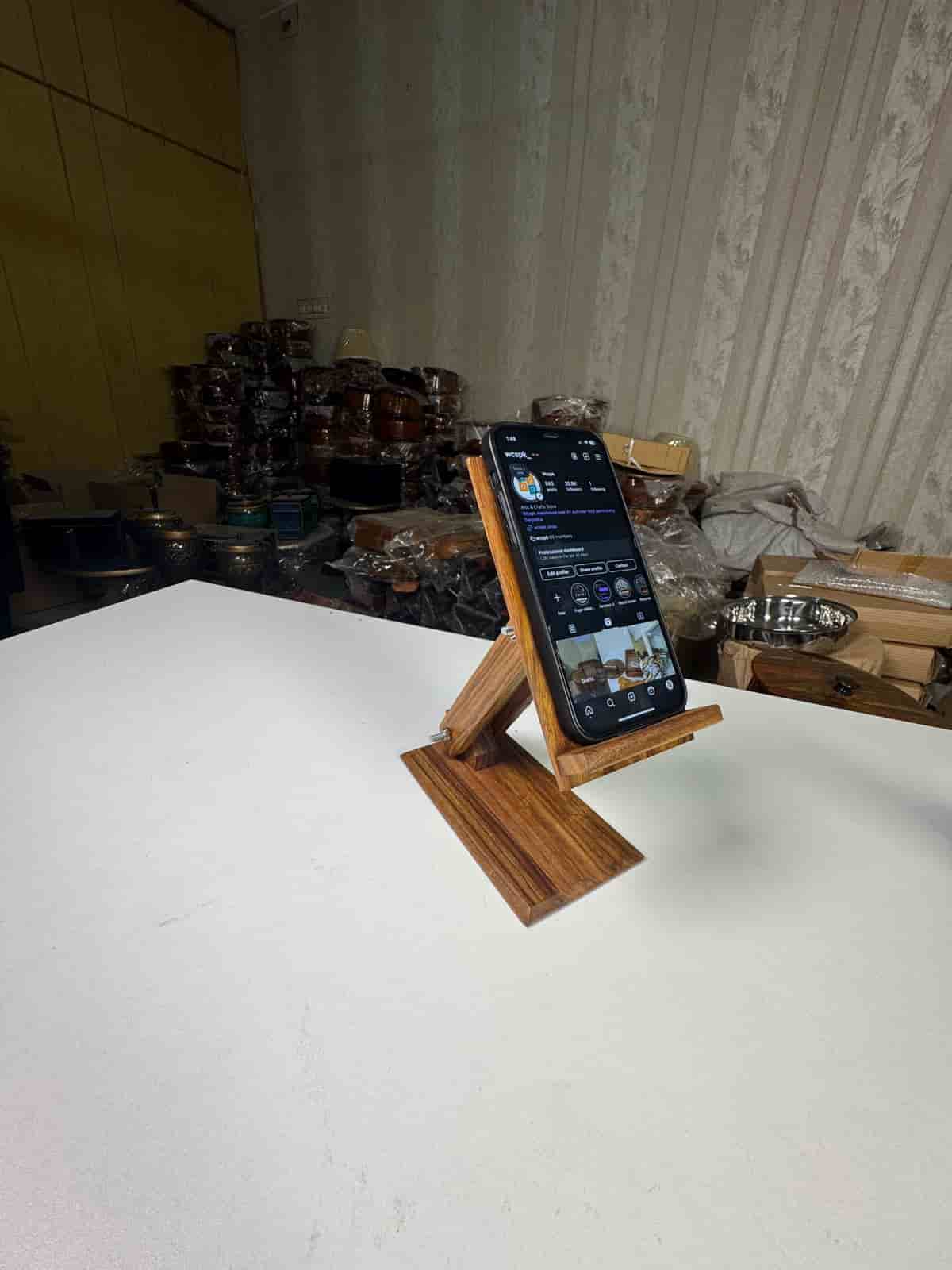 Handcrafted wooden mobile stand holding a smartphone on a desk